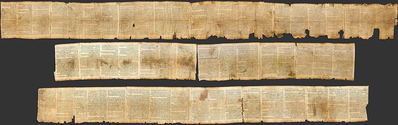 The Great Isaiah Scroll unrolled and photographed in three long sections against black, columns of Hebrew script running across the tan parchment, edges worn and stitched sheets visible.